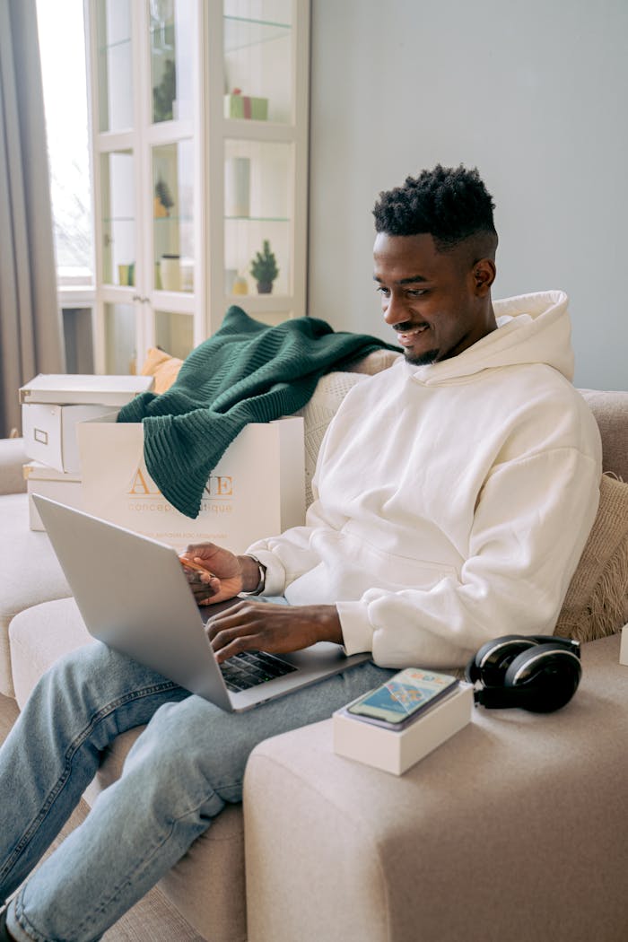 Crafting Captivating Headlines: Your awesome post title goes here Man using laptop in living room with shopping bags, enjoying online shopping.
